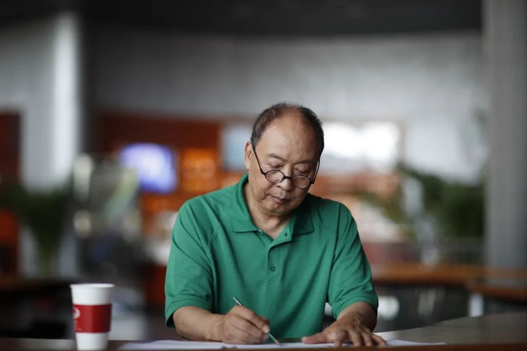 朱绍玉伏案执笔、伏案创作工作照（澎湃新闻“上海访谈”栏目配图）