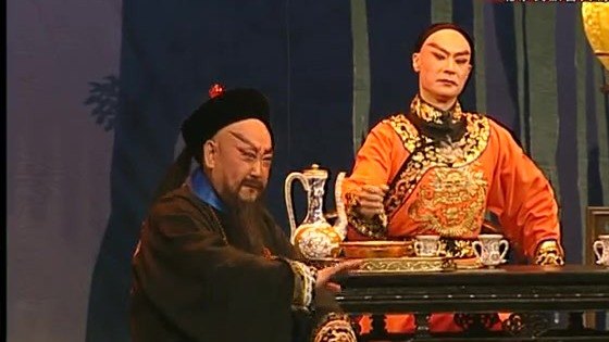 京剧《廉吏于成龙》演出照：对饮议事——二人对坐桌案，案上陈青花酒壶与酒杯