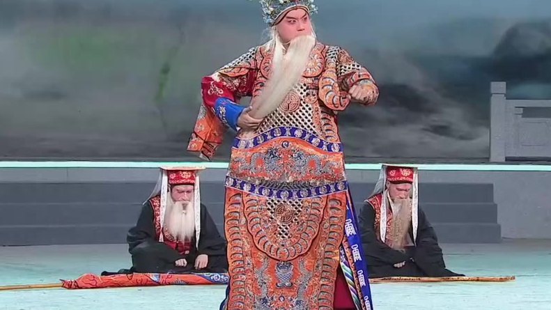 京剧《李陵碑》录像截帧：杨继业唱「七郎儿被潘洪箭射花标」，身后二随从跪地（表演：万琳）