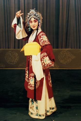 京剧《穆桂英挂帅》剧照：穆桂英红帔白裙、手托黄色砌末（国家京剧院官网剧目页所载）